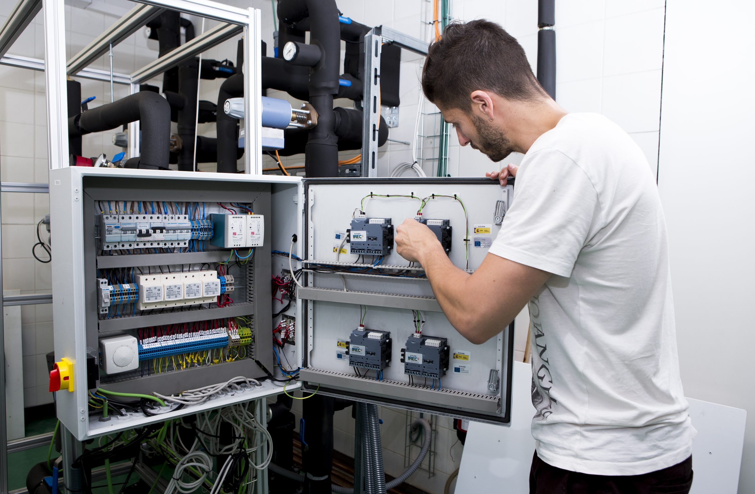 Scientist adjusting laboratory equipment for energy system modelling and decarbonisation pathway analysis, supporting research on retrofitting strategies, policy implementation and sustainable energy transitions.