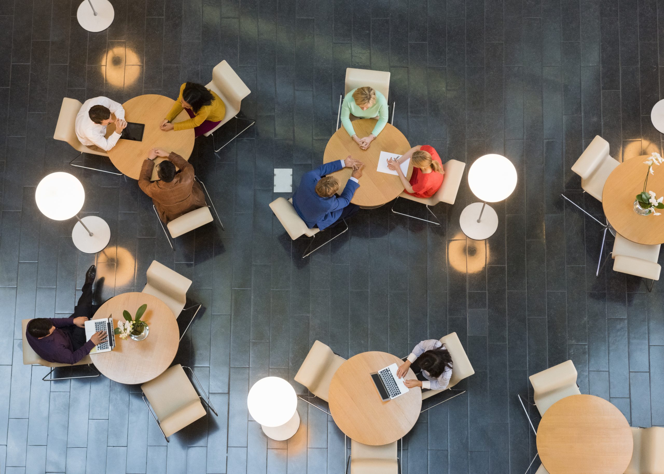 Aerial view of staff working at round tables in a shared hall, showcasing the robust IT systems and coordinated effort supporting IREC's research activities.